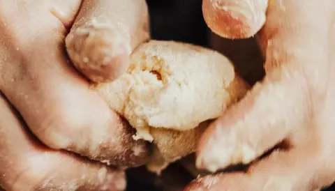 Hands kneading soft dough