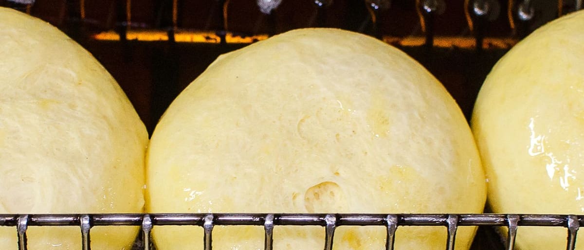 Trays of proofed dough balls on racks in the Hebbal bakehouse